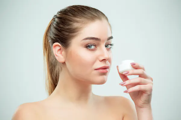 a woman holds an eye cream jar a woman holds an eye cream jar